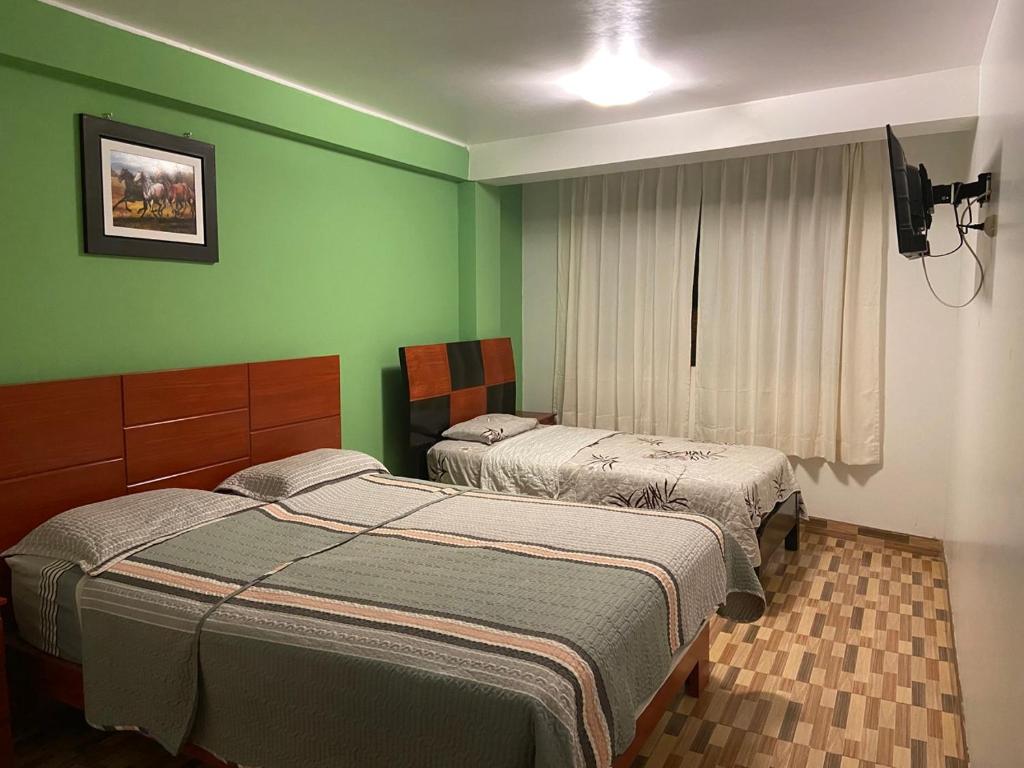 two beds in a room with green walls at Hotel Puerto Bayovar II in Mala