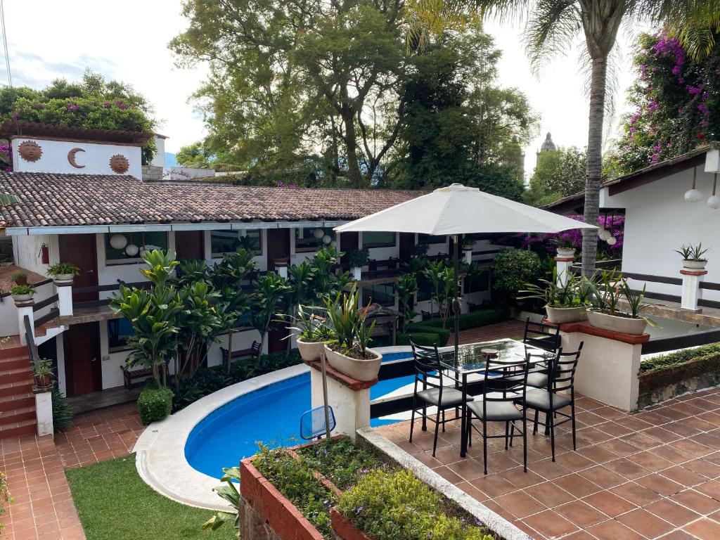 a patio with a table and umbrella next to a pool at Casa Dalinda in Valle de Bravo