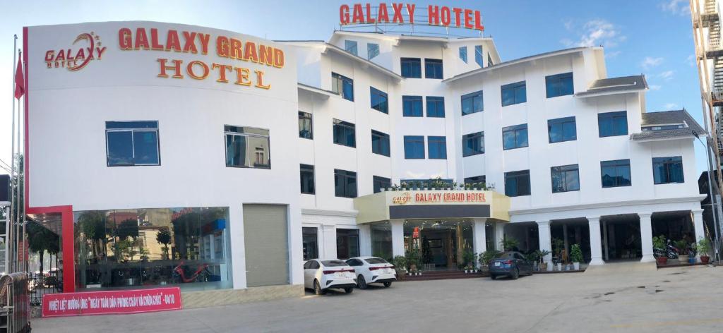 a large white hotel with cars parked in front of it at Galaxy Grand Hotel in Sơn La