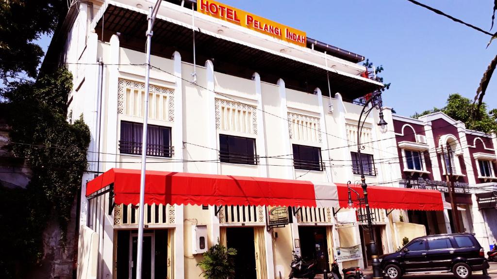 a white building with a red awning on a street at Hotel Pelangi Indah in Semarang