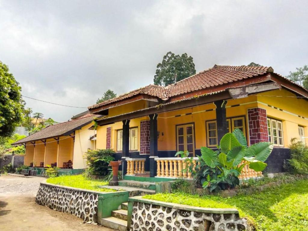 a yellow house with a garden in front of it at Nguntara Gati in Sleman