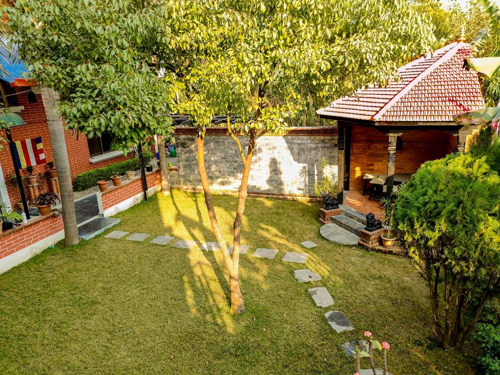 a small yard with a tree and a house at Hotel Ananda Inn in Lumbini