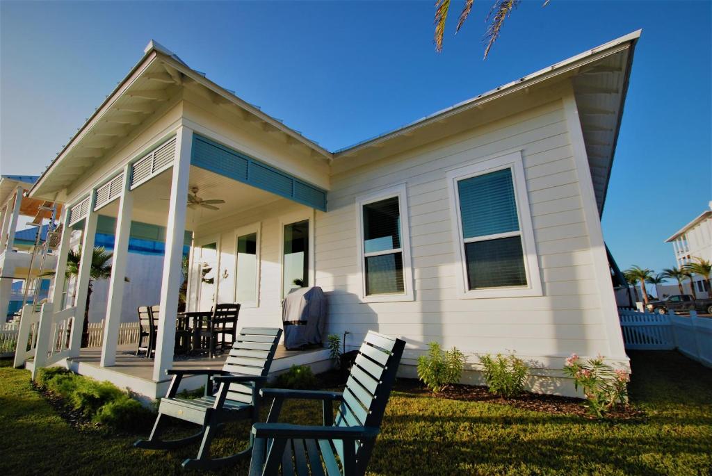 Casa blanca con sillas en el porche delantero en Anchors Aweigh cottage, en South Padre Island