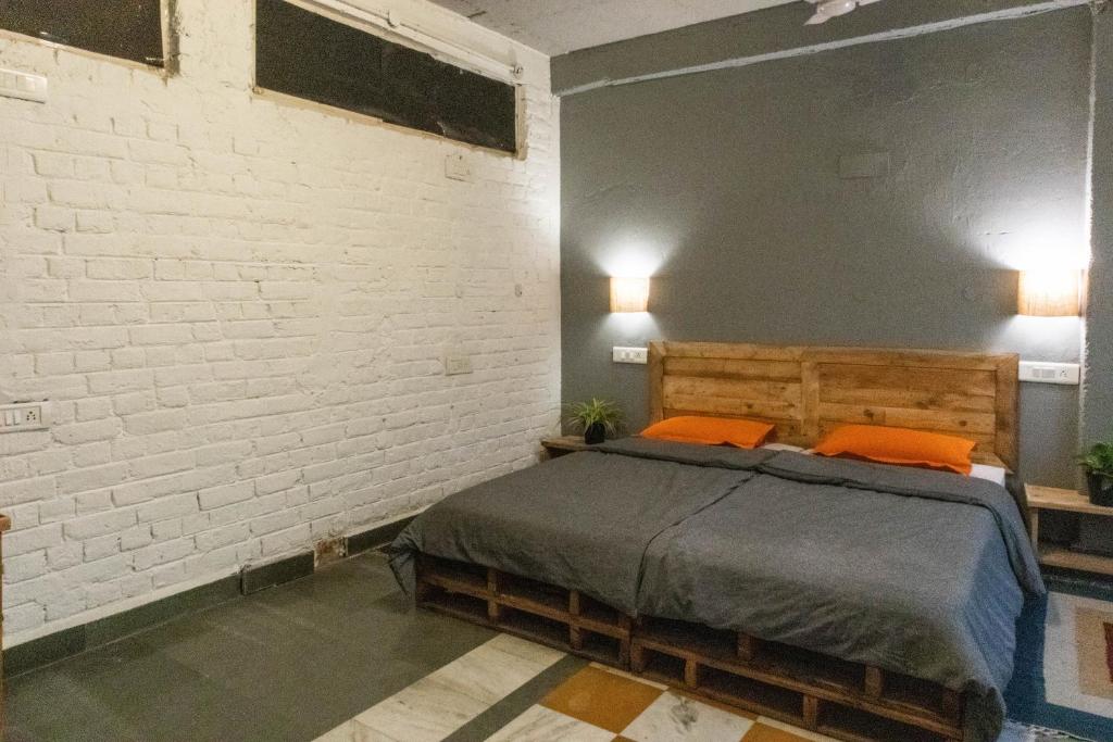a bedroom with a bed and a white brick wall at JHouse near Bhikaji in New Delhi