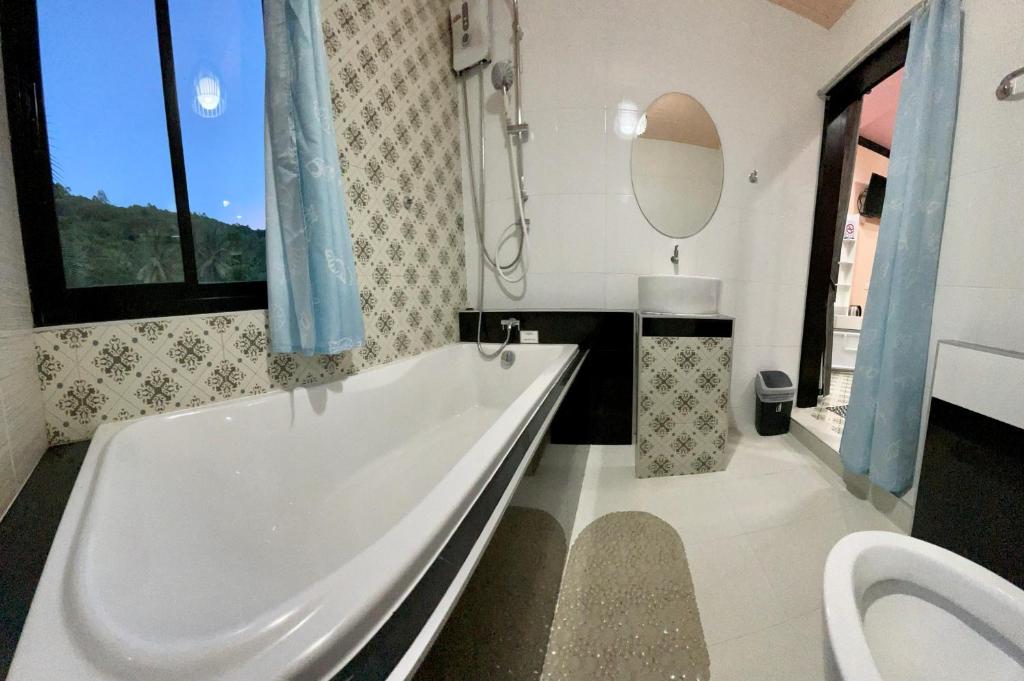 een badkamer met een bad, een wastafel en een spiegel bij คูร์โดวเเอนด์เเซนด์วิลล่า in Kiriwong