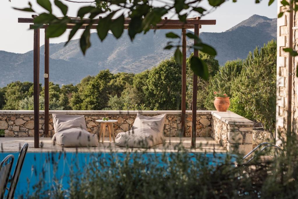 una piscina con almohadas y una mesa con vistas a las montañas en Koules Estate, simplicity & natural, By ThinkVilla, en Argoulión