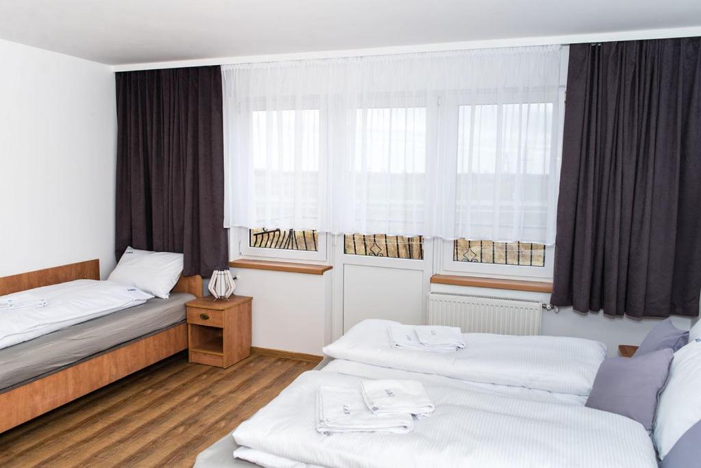 a hotel room with two beds and windows at Dom Wczasowy Larix in Rewal