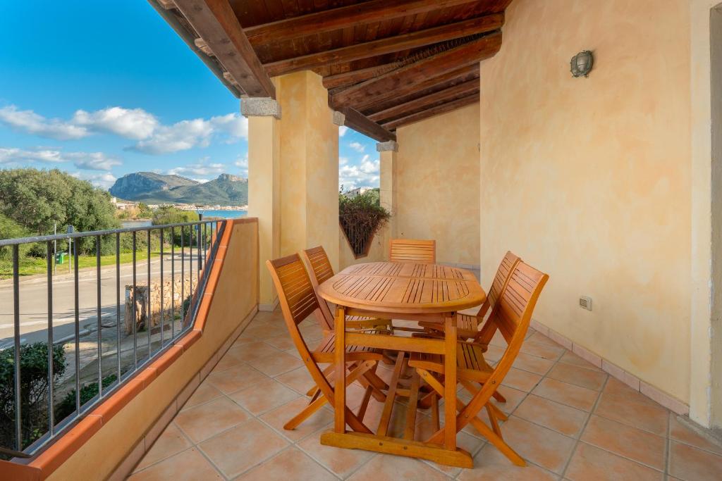 einen Holztisch und Stühle auf einem Balkon mit Aussicht in der Unterkunft Trilo Orizzonti 31 in Golfo Aranci