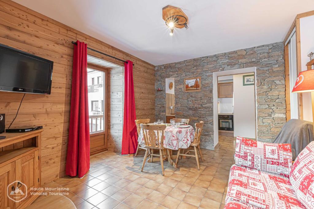 ein Wohnzimmer mit einem Tisch und einem TV in der Unterkunft 153 Rue des Rochers in Lanslevillard