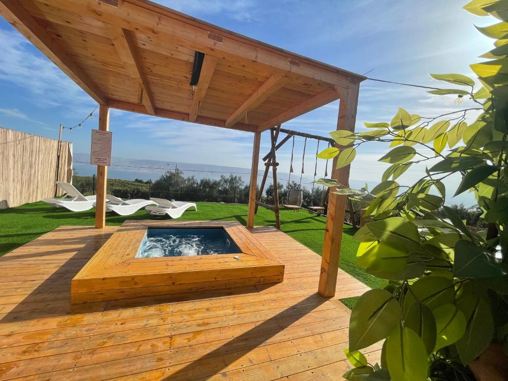 une terrasse en bois avec un bain à remous sous un toit en bois dans l'établissement נוף המצוק, à Poriyya
