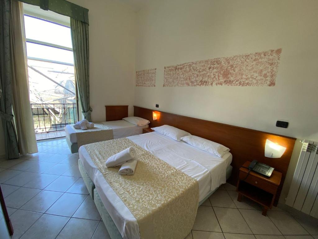 ナポリにあるHotel Eliseo Napoliのベッド2台と窓が備わるホテルルームです。