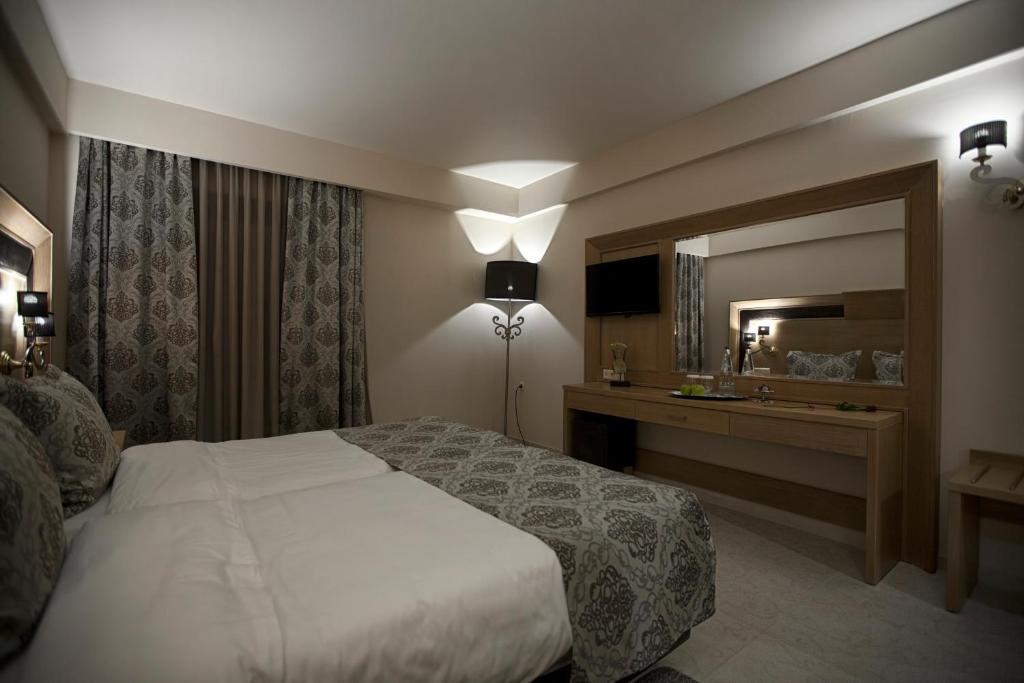 a hotel room with a bed and a mirror at Grand Meteora Hotel in Kalabaka