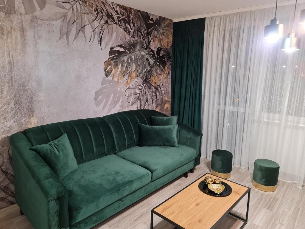 a green couch in a living room with a table at Apartament Nova przy S3 in Nowa Sól