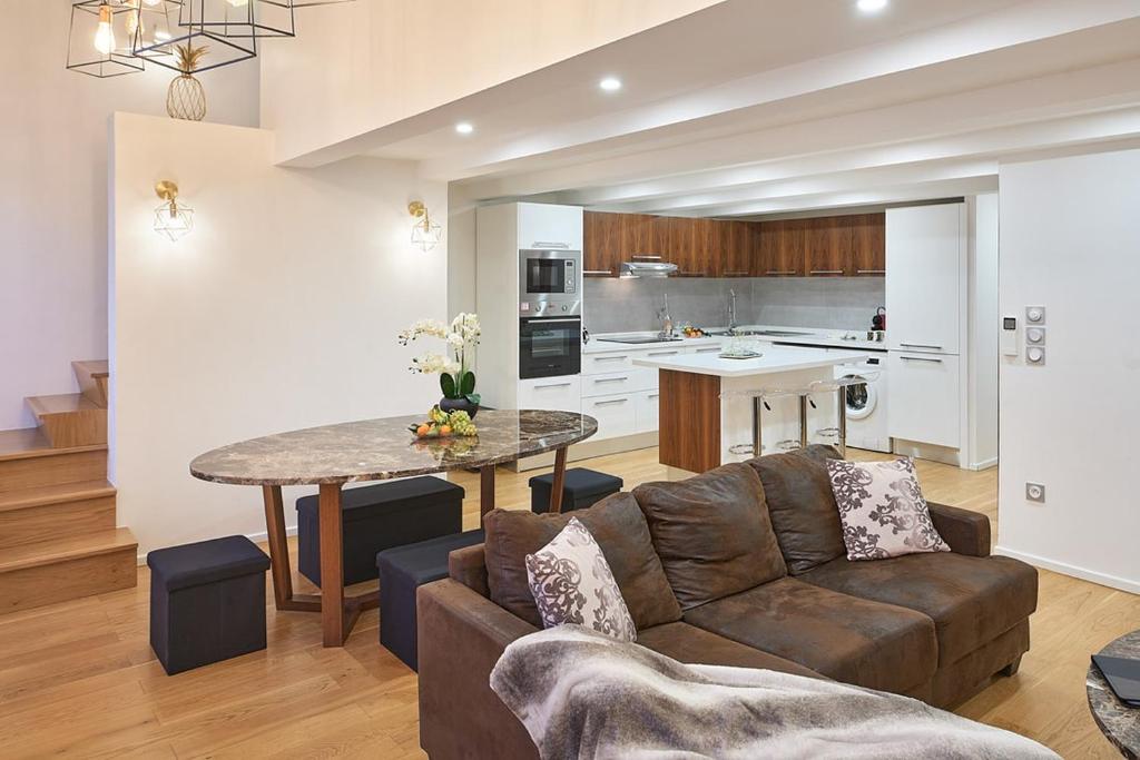 un salon avec un canapé et une table et une cuisine dans l'établissement Sunlight Properties - Palme D Or - 2 Bedrooms, modern holiday rental apartment, hyper central, à Cannes