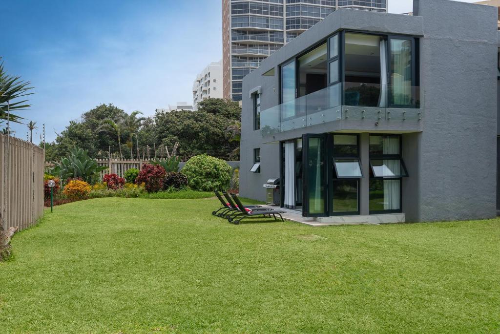 ein Haus mit zwei Stühlen auf einem Rasen in der Unterkunft Licorna Beach in Durban