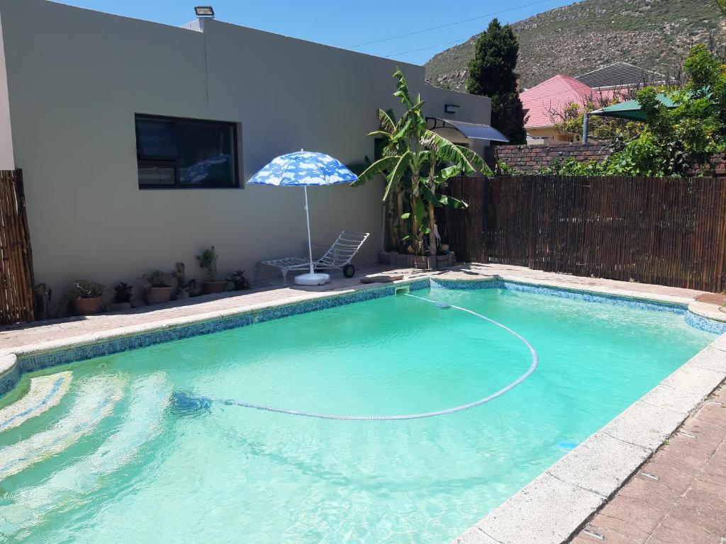 a swimming pool with an umbrella next to a house at The Pool Cottage in Fish hoek