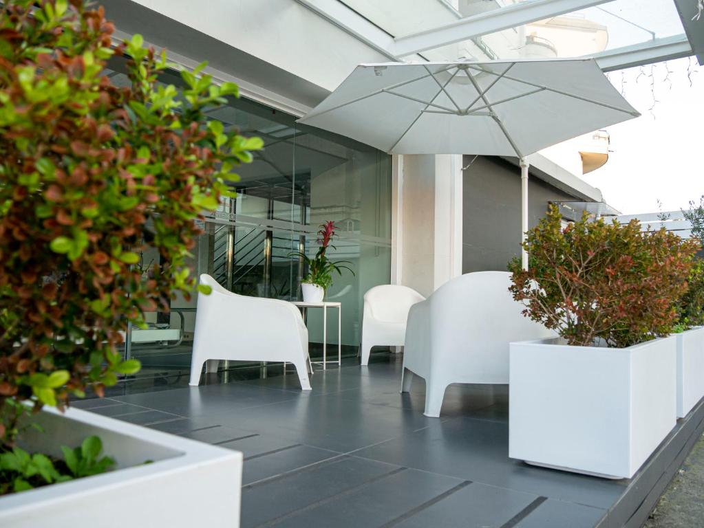 patio z białymi krzesłami i stołem z parasolem w obiekcie Hotel Artemide w mieście Aversa