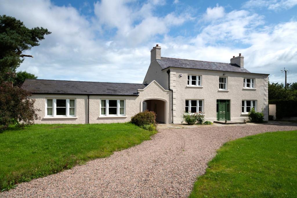 una gran casa blanca con una entrada de grava en Knockanboy House, en Ballymoney