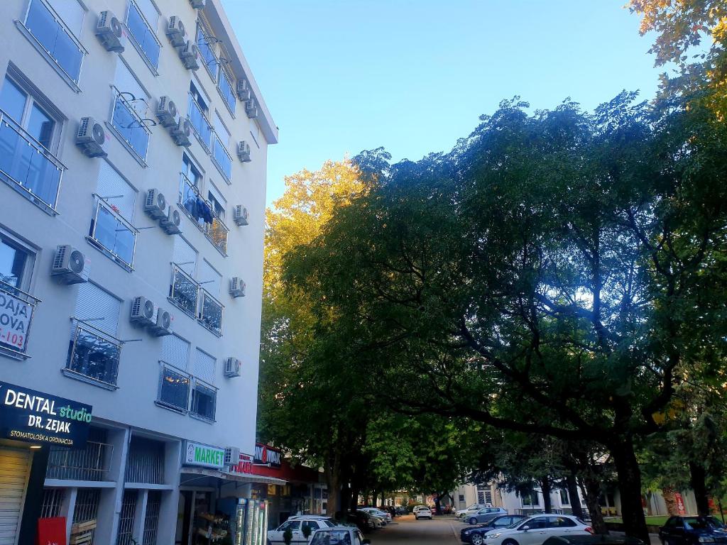 ein hohes weißes Gebäude mit einem Baum neben einer Straße in der Unterkunft City Center & Seaside LUX Apartment in Bar