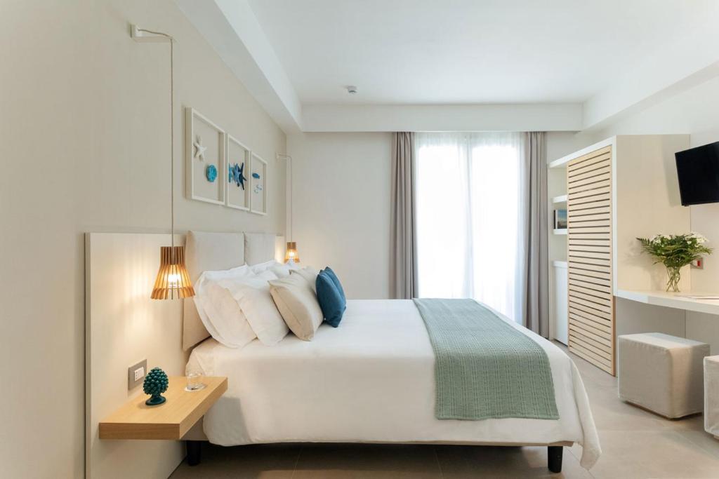 a white bedroom with a large bed and a table at Albatros Beach Hotel in Letojanni