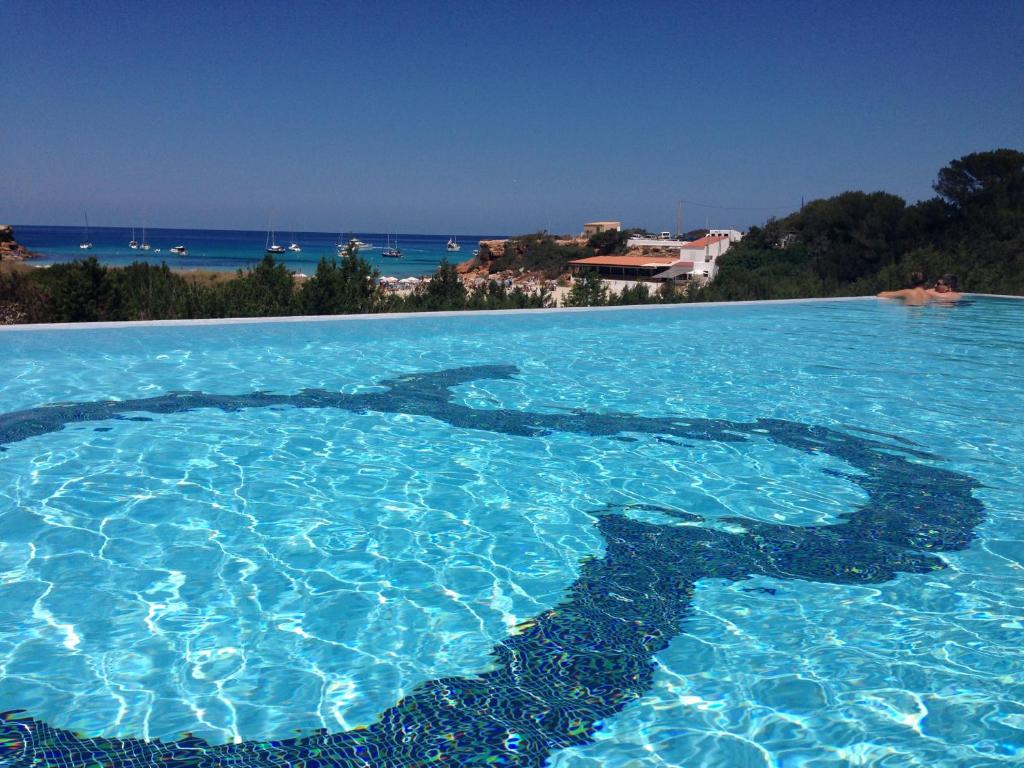 a swimming pool with a large blue pool in the middle of it at Hotel Cala Saona & Spa in Cala Saona