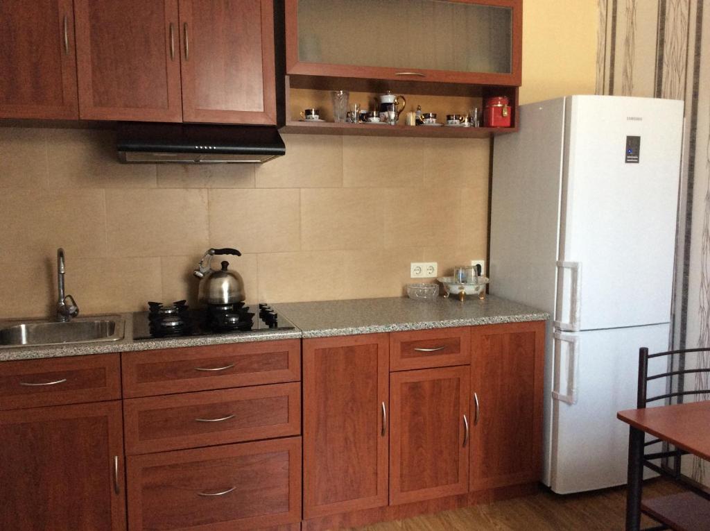 a kitchen with wooden cabinets and a white refrigerator at Studio Lermontov Street in Tbilisi City