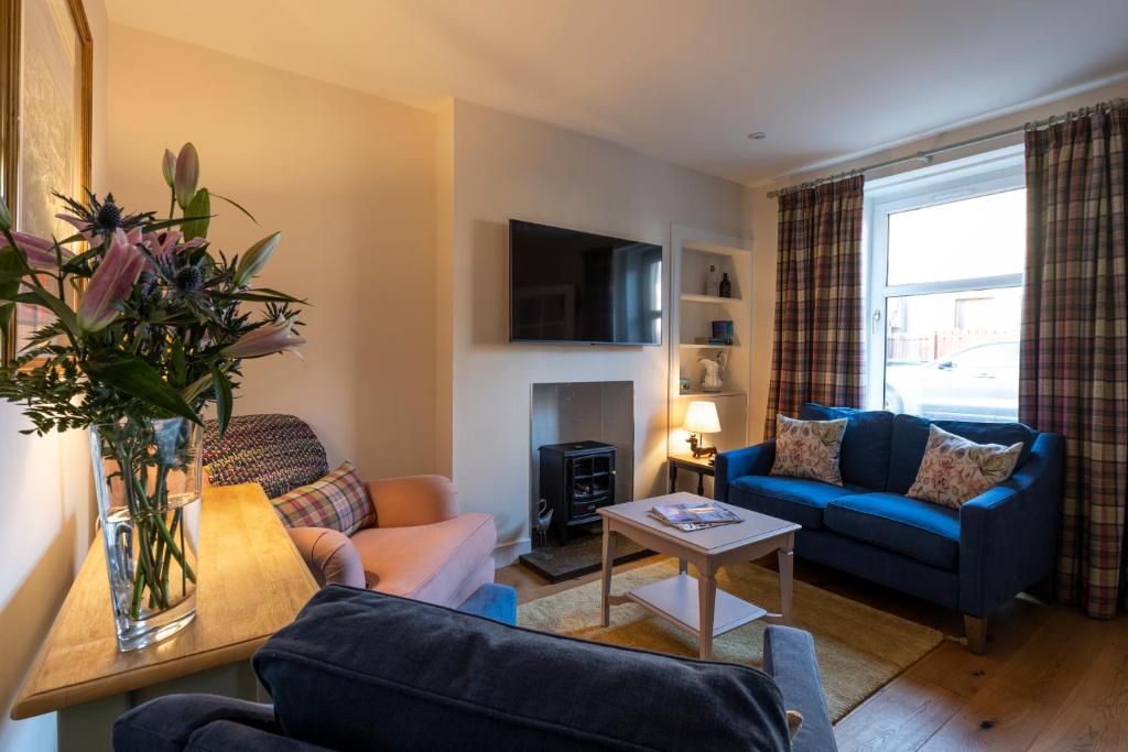 uma sala de estar com um sofá azul e uma mesa em Celt Cottage em Inverness
