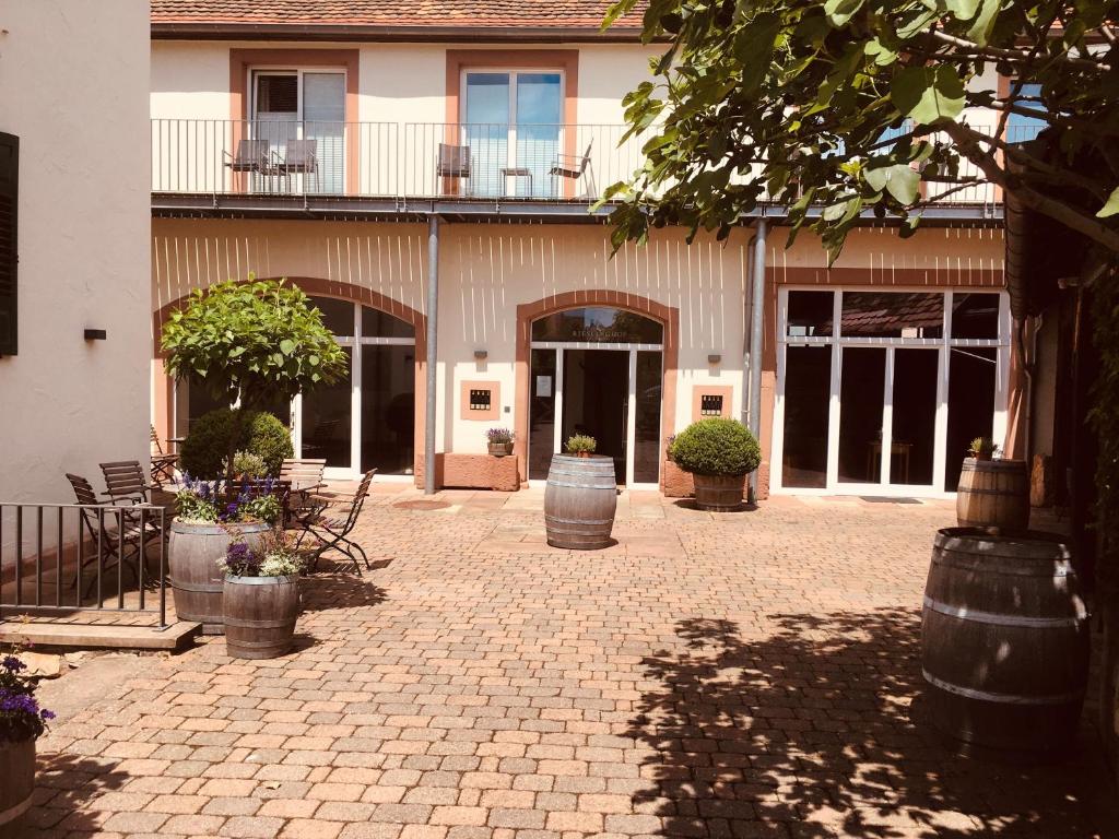 un patio con un edificio con puertas y flores en Rieslinghof en Wachenheim an der Weinstraße