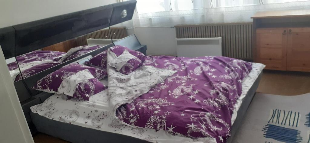 a bed with a purple and white comforter and pillows at Bajina Basta stan na dan in Bajina Bašta