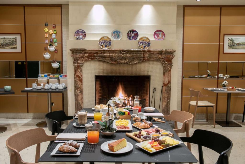 a table with food in front of a fireplace at Hotel Cappello D'Oro, BW Signature Collection in Bergamo