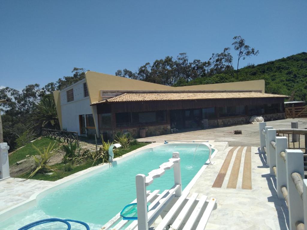 a swimming pool with chairs and a building at Hotel fazenda Pousada Fazendinha beach club arraial do cabo in Arraial do Cabo