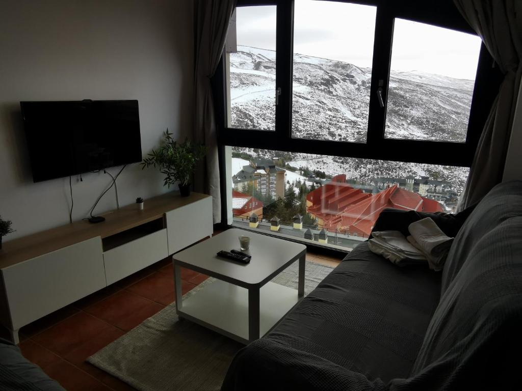 a living room with a couch and a large window at Apartamento en Sierra Nevada, próximo a pistas y plaza central, vistas increíbles in Sierra Nevada