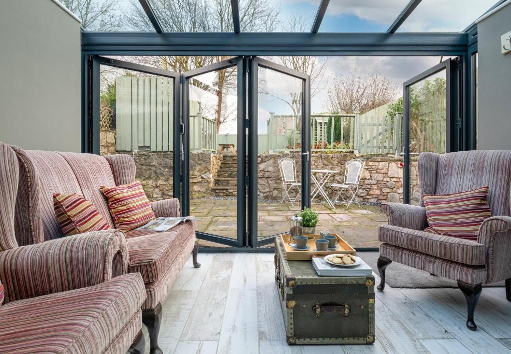 a conservatory with two couches and a table at Finest Retreats - Esmor Cottage in Caerwys