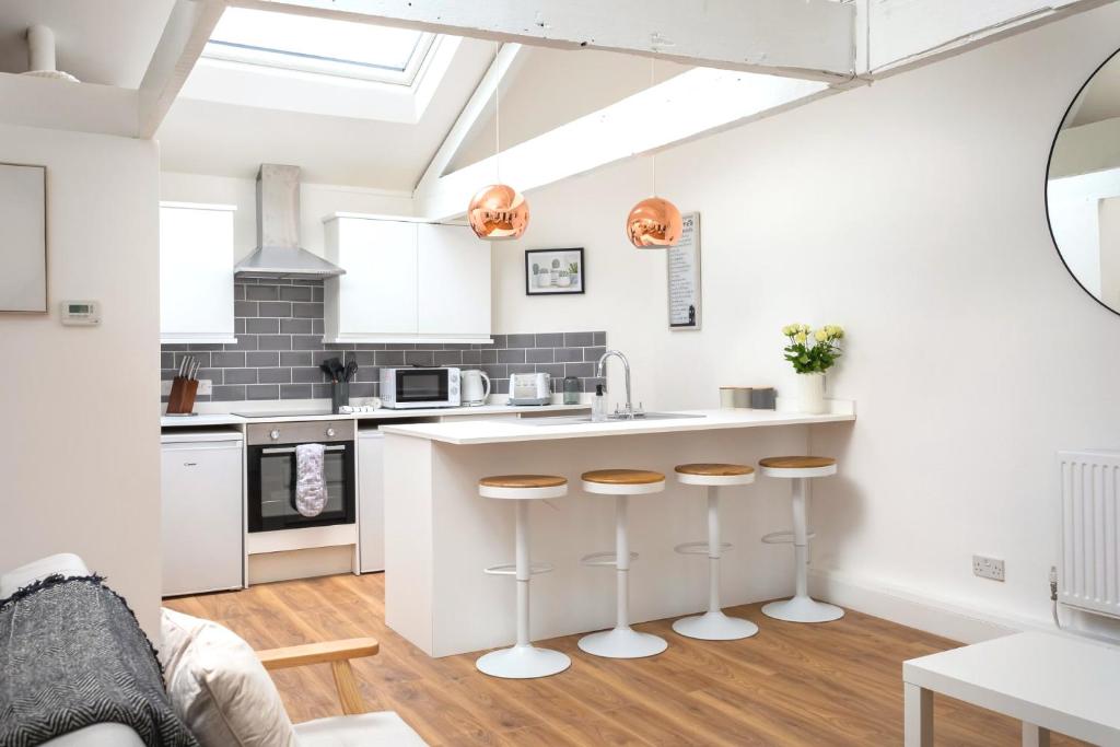 a kitchen with white cabinets and a counter with stools at Curb Properties - Cool Trendy Montpellier Apartment in Cheltenham