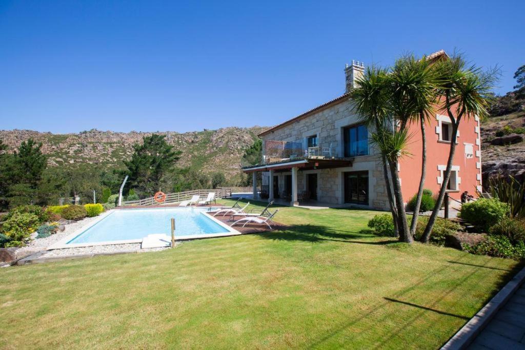 una casa con una piscina y una palmera en A Ballenera de Caneliñas, en Cee