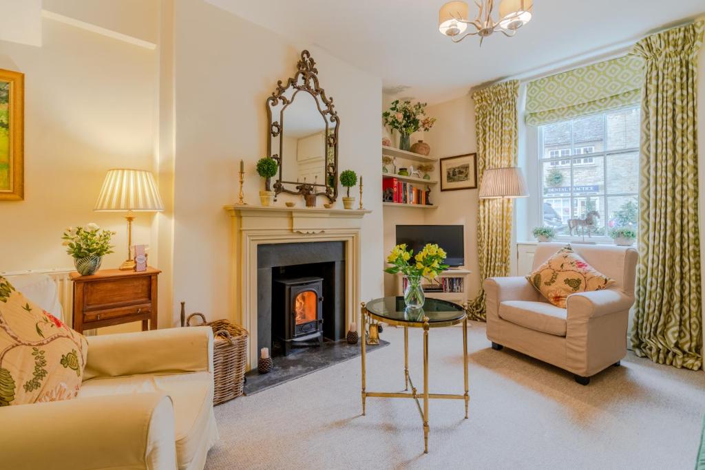 a living room with a fireplace and a table at New Church Cottage in Tetbury