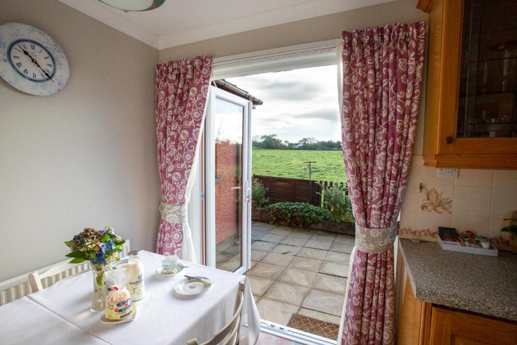 eine Küche mit Tisch und Tür zu einer Terrasse in der Unterkunft Goitre Bach Cottage in Aberaeron