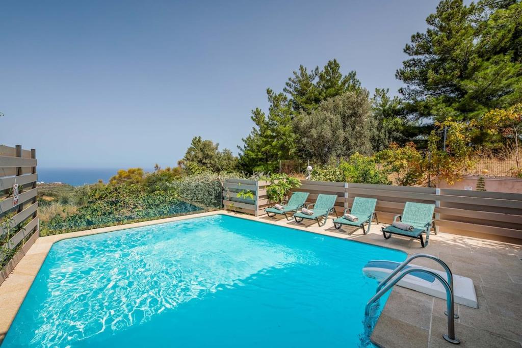 una piscina con 2 tumbonas junto a ella en Mikra Anogia Villas, en Rethymno