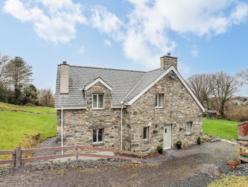 a stone house with a fence in front of it at Craigfa Cottage in Bangor