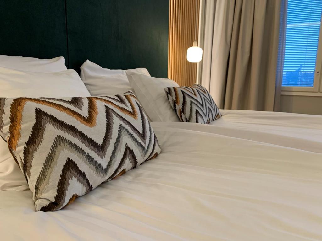 Una cama blanca con almohadas de cebra. en Park Hotel Tornio en Tornio