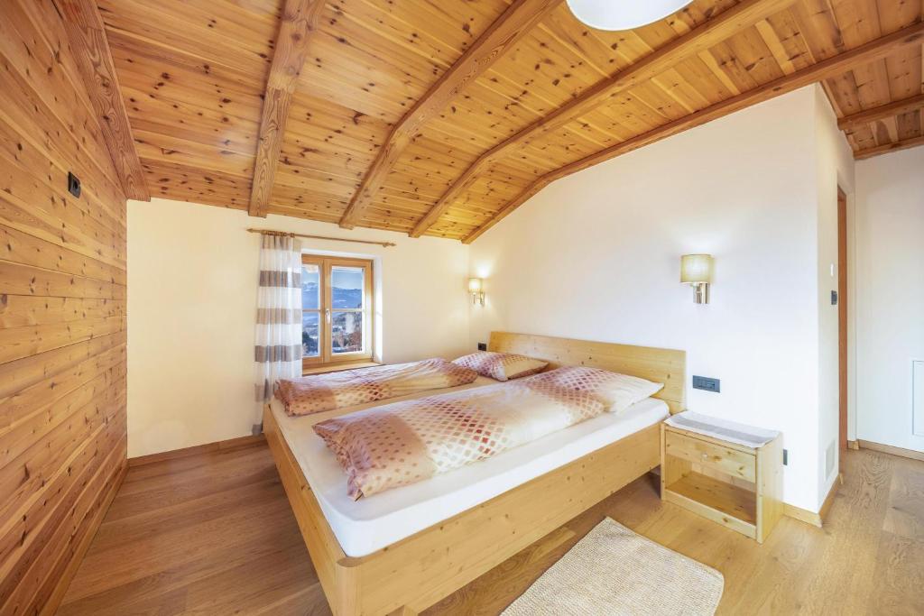 Bett in einem Zimmer mit Holzdecke in der Unterkunft Malgorerhof Sonja in Jenesien
