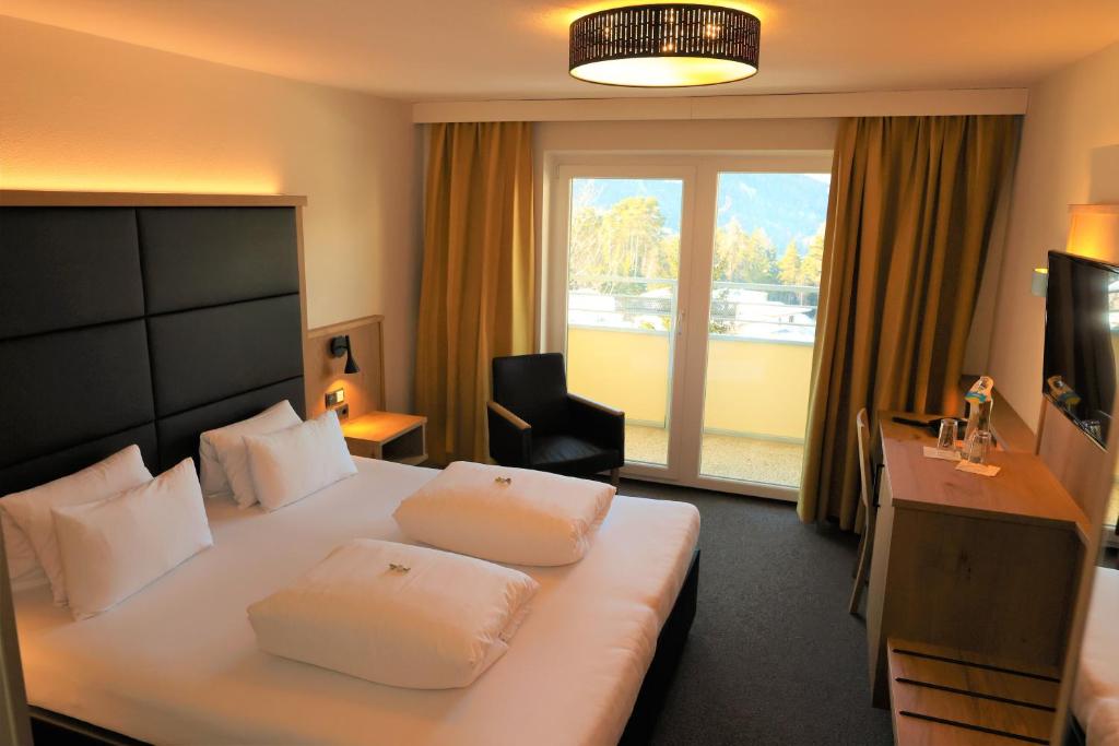 Habitación de hotel con cama, escritorio y ventana en Hotel Arzlerhof en Arzl im Pitztal