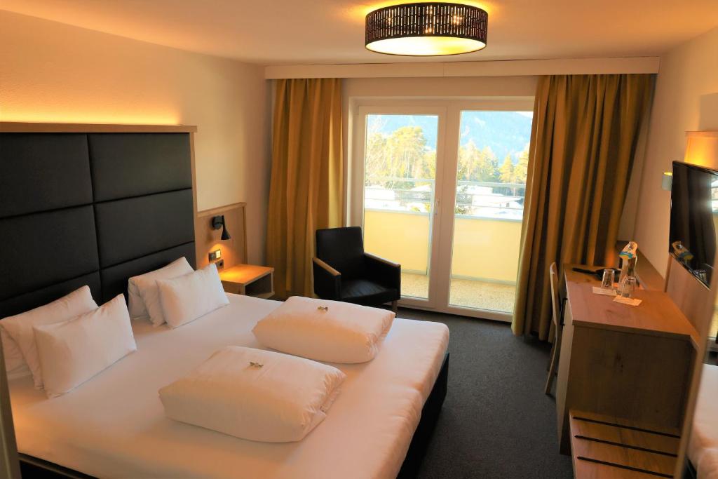 a hotel room with a bed and a desk and a window at Hotel Arzlerhof in Arzl im Pitztal