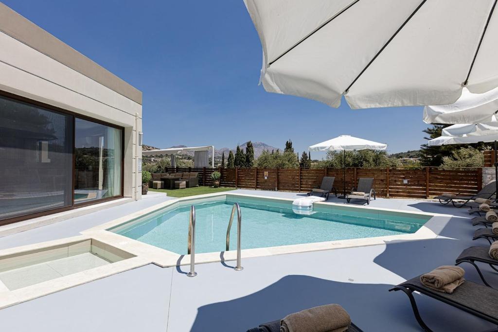 a swimming pool in a house with an umbrella at Villa Chnaris - Private Pool and Sauna in Perama