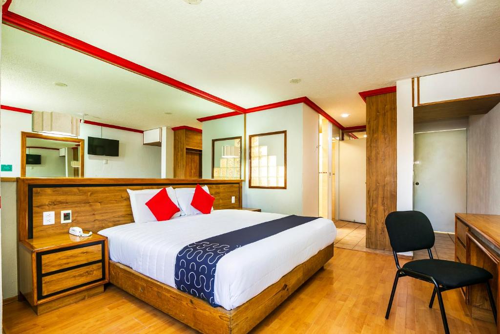 a bedroom with a large bed with red pillows at Capital O Hotel Casa Blanca, Morelia in Morelia