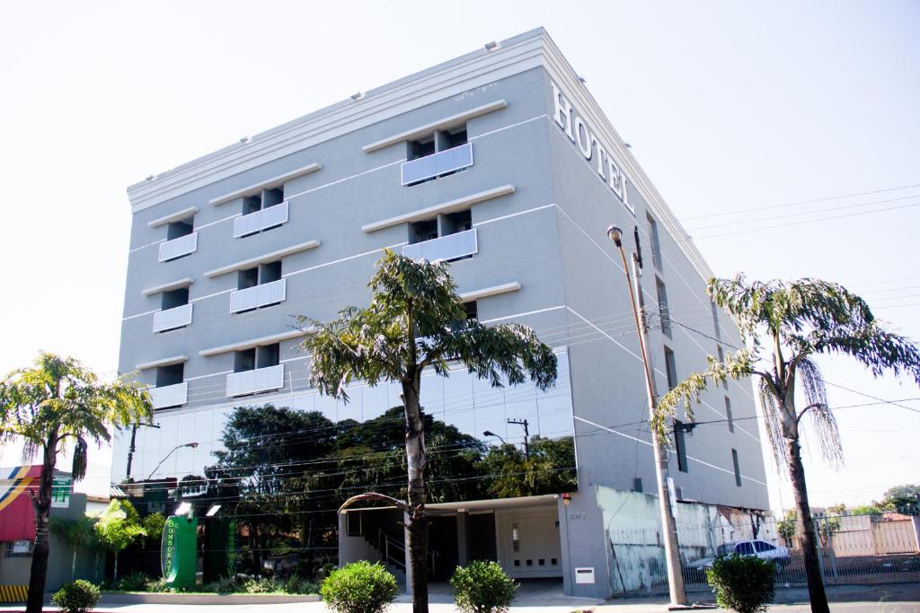 un edificio bianco con palme di fronte di BOMBONATO PALACE HOTEL a Uberaba