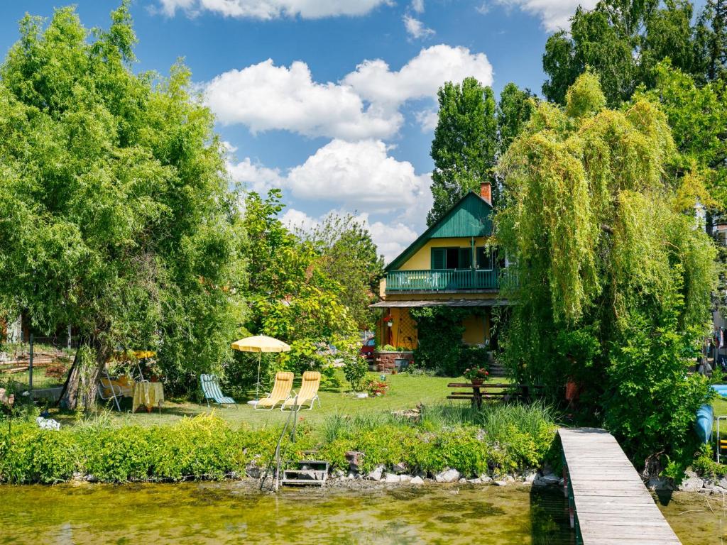 une maison au bord de la rivière avec un pont et des chaises dans l'établissement Apartment Sunset by Interhome, à Szántód