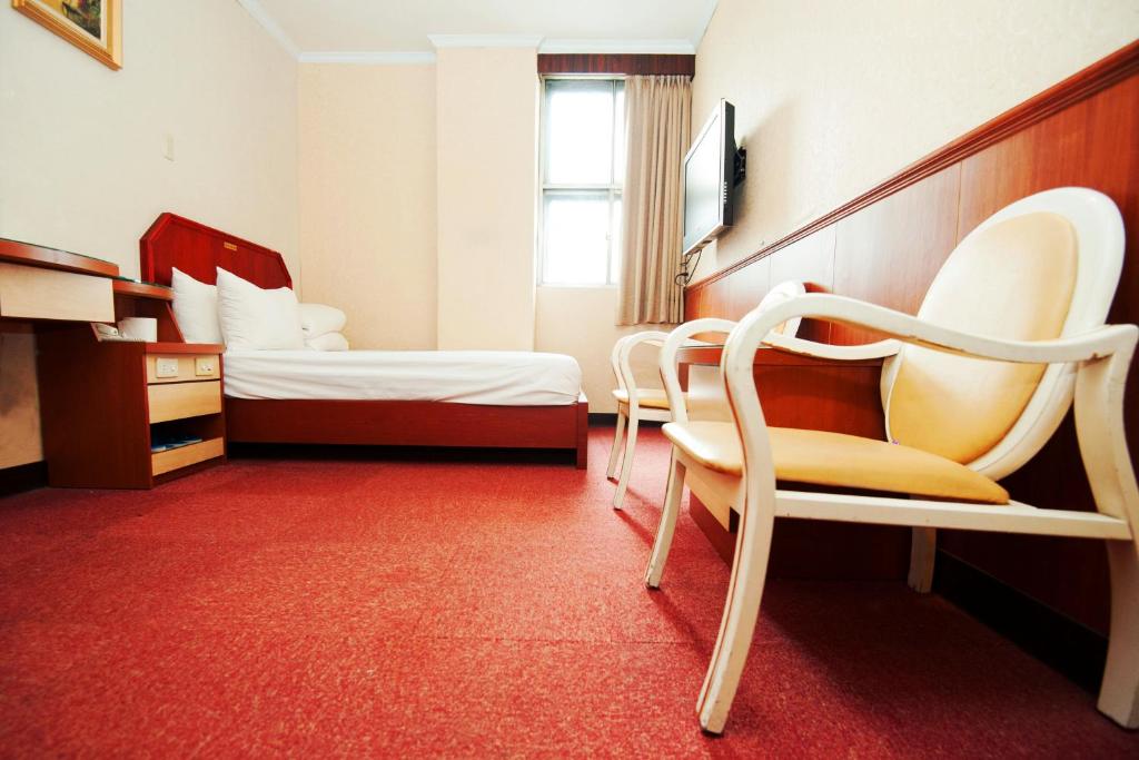 ein Hotelzimmer mit 2 Betten und einem Stuhl in der Unterkunft New May Flower Hotel in Taipeh