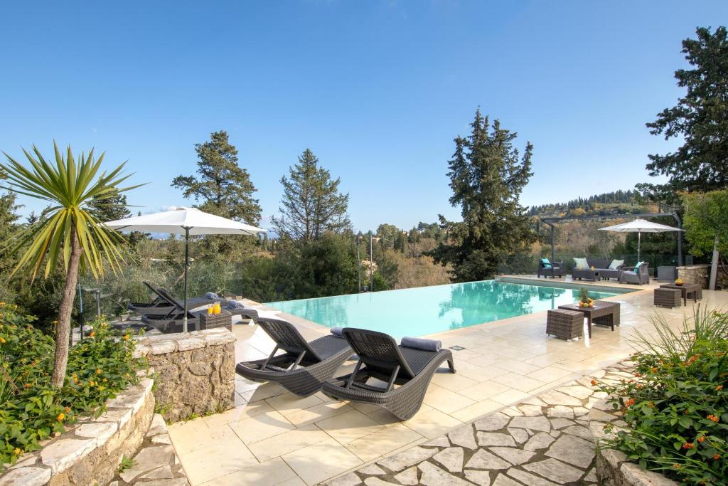 a pool with chairs and umbrellas in a yard at Villa Iremia by Rodostamo Collection in Gazátika