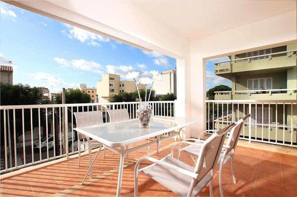 y balcón con mesa de comedor blanca y sillas. en Marcos Apartment en Port de Pollensa